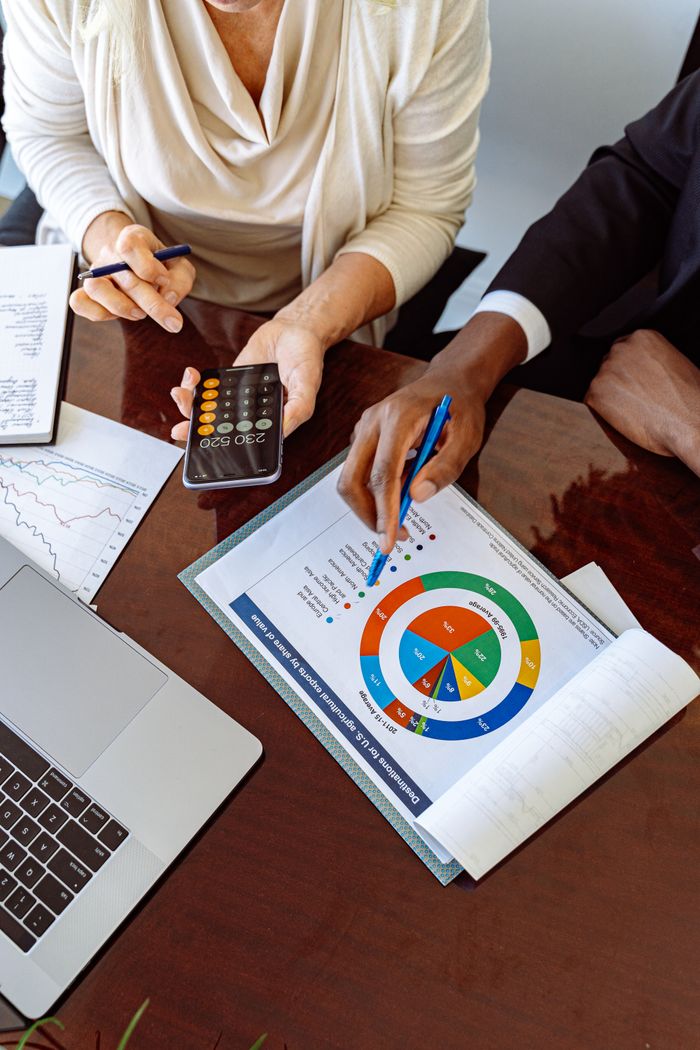 our-experience Two business professionals discussing financial documents and strategies at an office desk.