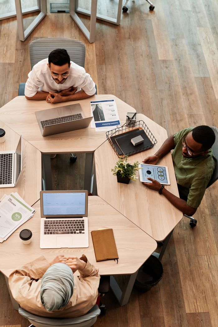 Crafting Captivating Headlines: Your awesome post title goes here Top view of diverse team engaged in discussion with laptops and digital devices in modern office setting.