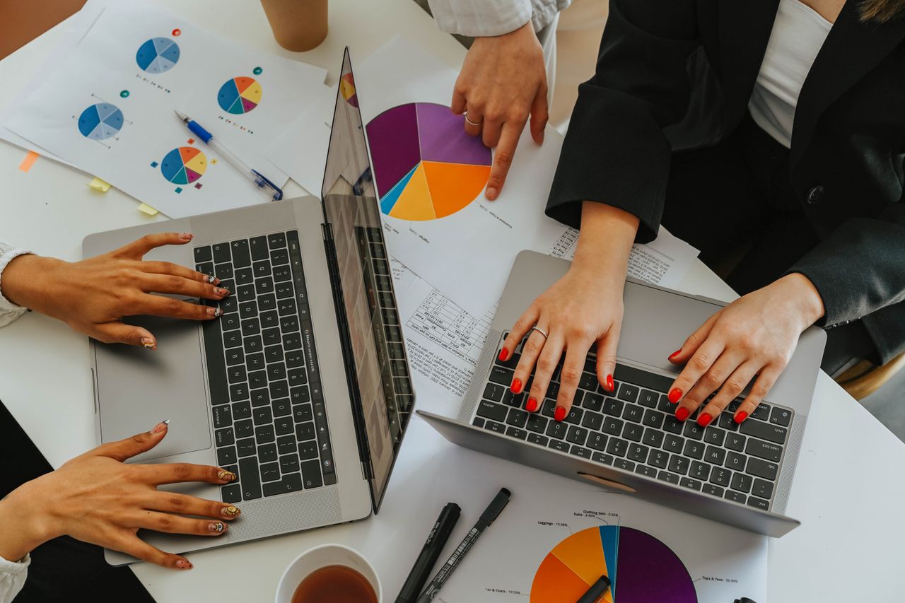 The Art of Drawing Readers In: Your attractive post title goes here Top view of women working together on laptops with business charts at a white office table.